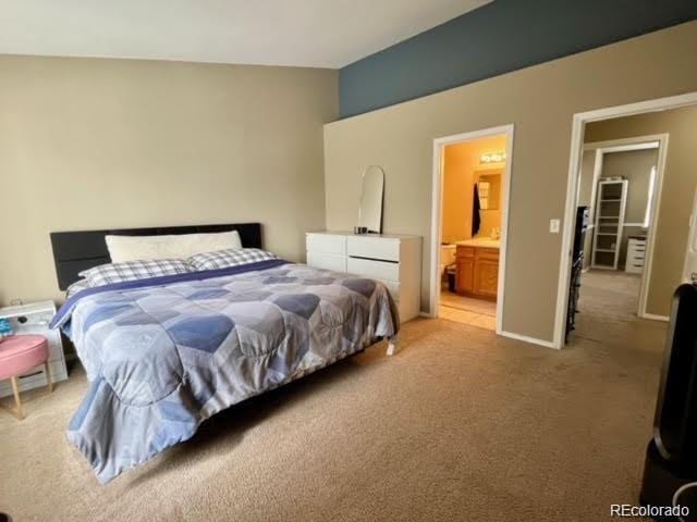 bedroom with ensuite bath, baseboards, and light carpet