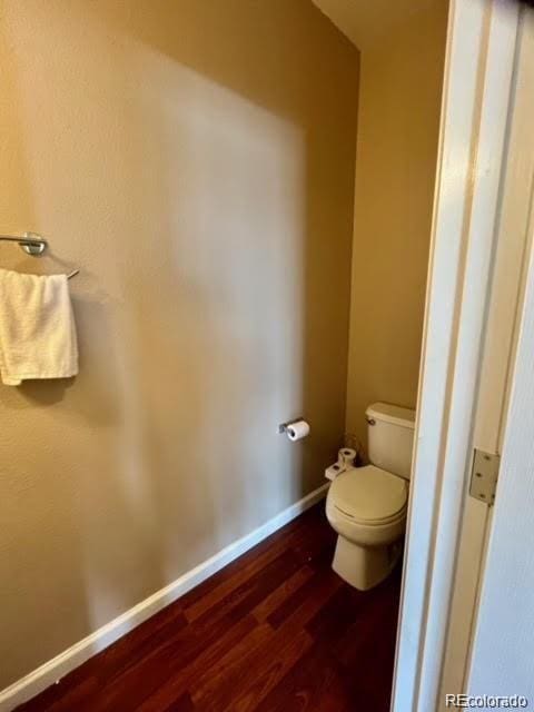 bathroom with toilet, wood finished floors, and baseboards