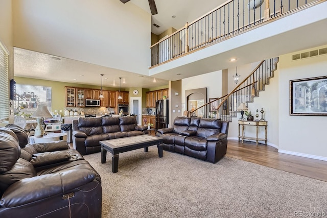 living room with a high ceiling, ceiling fan, and hardwood / wood-style flooring