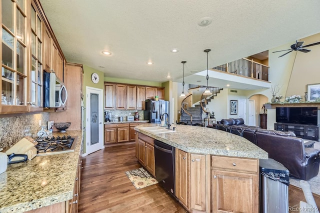 kitchen featuring a center island with sink, dark hardwood / wood-style floors, stainless steel appliances, and decorative backsplash