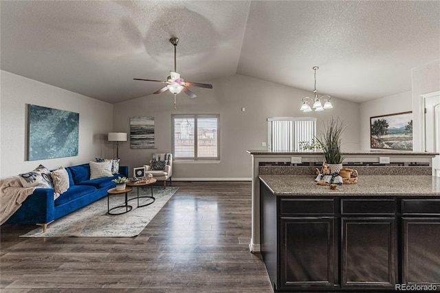 kitchen with lofted ceiling, dark hardwood / wood-style floors, ceiling fan with notable chandelier, and a textured ceiling