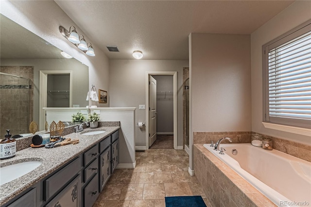 bathroom featuring vanity, separate shower and tub, and a textured ceiling