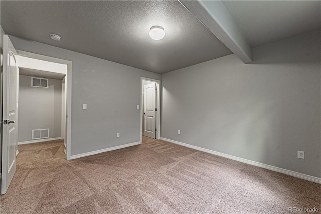 unfurnished bedroom featuring beam ceiling, light colored carpet, and a textured ceiling