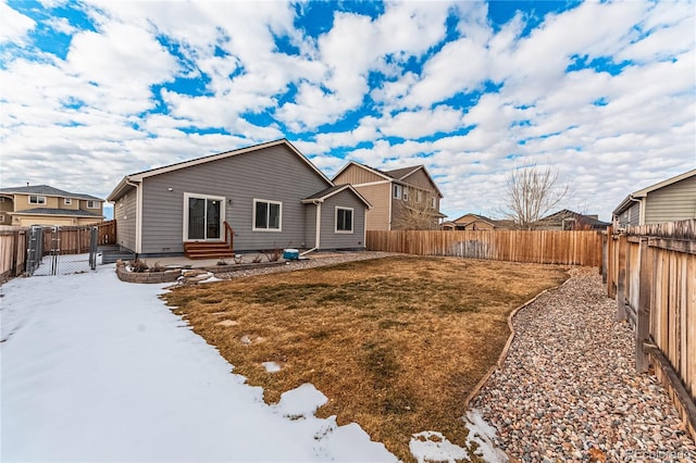 snow covered back of property with a patio and a lawn