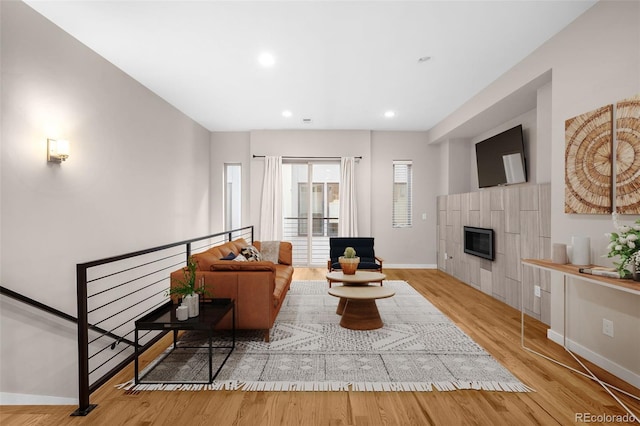 living room featuring a tiled fireplace and light hardwood / wood-style flooring