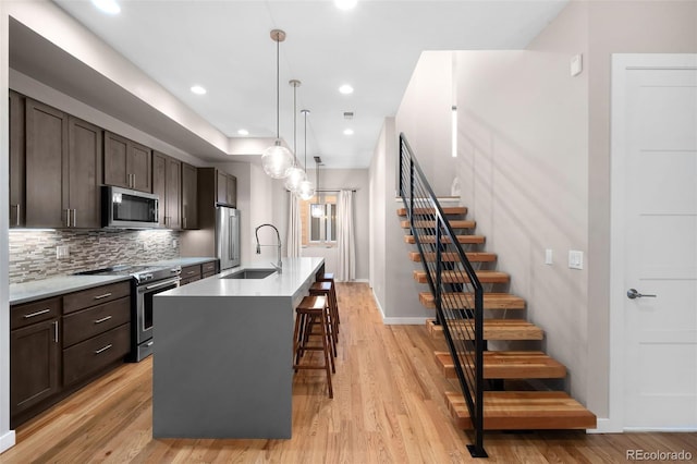 kitchen featuring sink, a breakfast bar area, hanging light fixtures, a kitchen island with sink, and stainless steel appliances