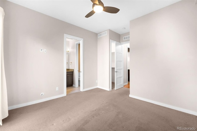 unfurnished bedroom with ensuite bathroom, light colored carpet, and ceiling fan