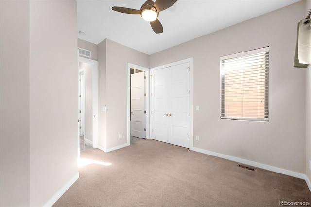 unfurnished bedroom featuring light colored carpet, a closet, and ceiling fan