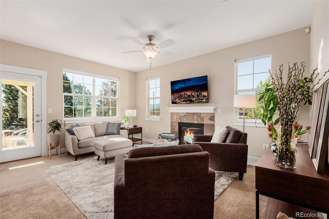 living room with ceiling fan, light colored carpet, and a tile fireplace