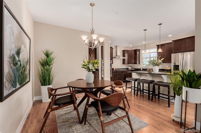 dining area with sink, a notable chandelier, and light wood-type flooring