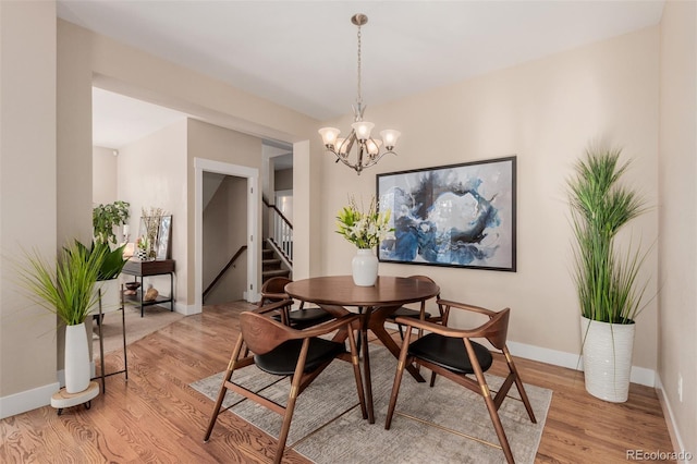 dining space featuring light wood-type flooring and a notable chandelier