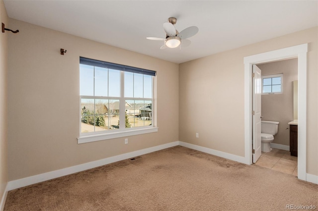 unfurnished bedroom with ceiling fan, ensuite bathroom, and light colored carpet