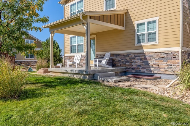 doorway to property with a porch and a lawn