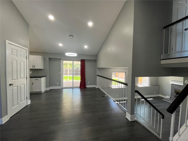 15962 E Exposition Dr, Aurora, CO 80017 - unfurnished living room with dark wood-type flooring, high vaulted ceiling, a brick fireplace, and recessed lighting