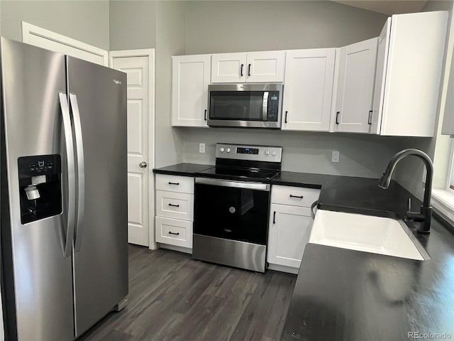 15962 E Exposition Dr, Aurora, CO 80017 - kitchen featuring appliances with stainless steel finishes, white cabinetry, dark wood finished floors, vaulted ceiling, and dark countertops