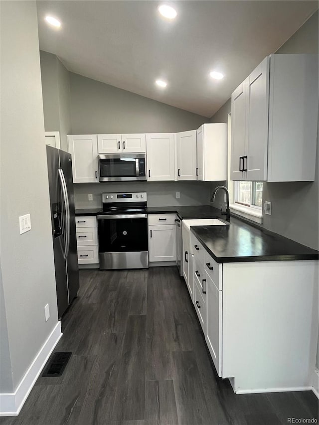 15962 E Exposition Dr, Aurora, CO 80017 - kitchen with stainless steel appliances, dark countertops, lofted ceiling, white cabinets, and dark wood-type flooring