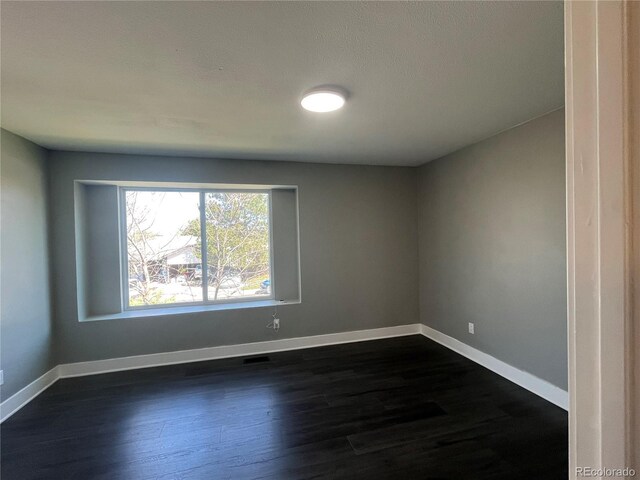 15962 E Exposition Dr, Aurora, CO 80017 - spare room featuring baseboards and dark wood-style flooring