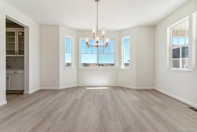 unfurnished dining area with light hardwood / wood-style floors and an inviting chandelier