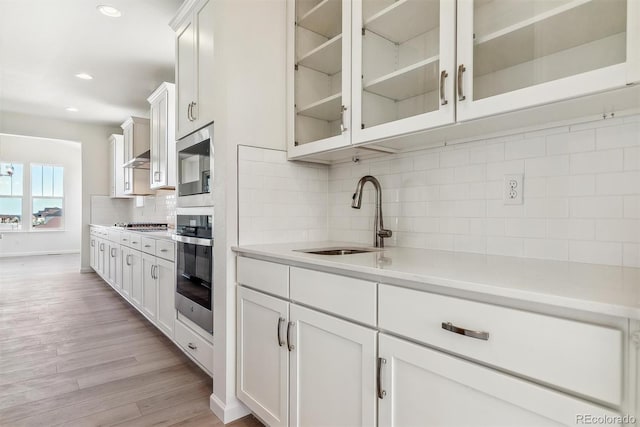 kitchen featuring sink, white cabinetry, stainless steel appliances, and light wood-type flooring