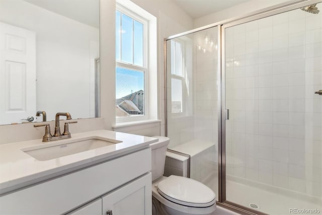 bathroom featuring vanity, a shower with shower door, and toilet