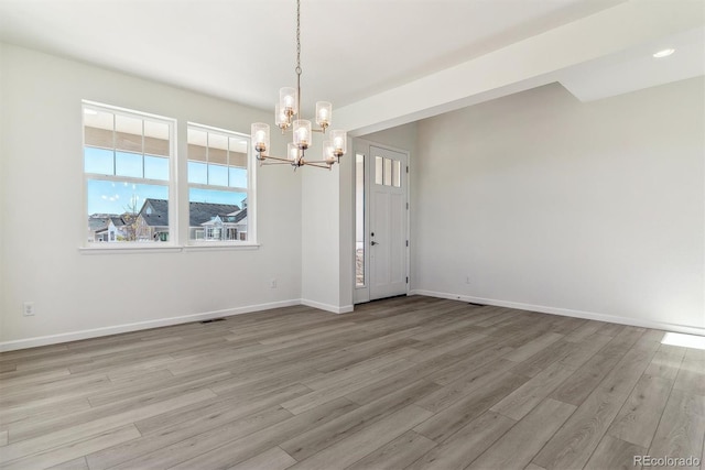 spare room with light hardwood / wood-style floors and an inviting chandelier