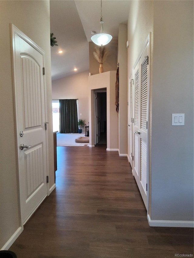 corridor featuring dark wood-type flooring and vaulted ceiling