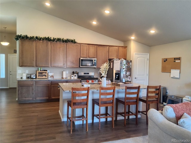 kitchen featuring stainless steel appliances, dark hardwood / wood-style floors, lofted ceiling, a breakfast bar, and a center island with sink