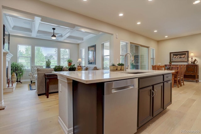 kitchen featuring coffered ceiling, stainless steel dishwasher, a kitchen island with sink, beamed ceiling, and light hardwood / wood-style floors