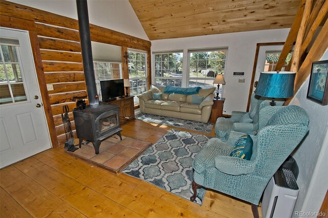 living room featuring a wood stove, wood-type flooring, lofted ceiling, and a healthy amount of sunlight