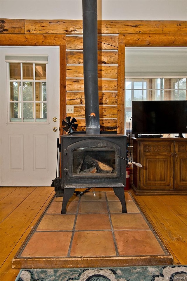 details with log walls, hardwood / wood-style flooring, and a wood stove