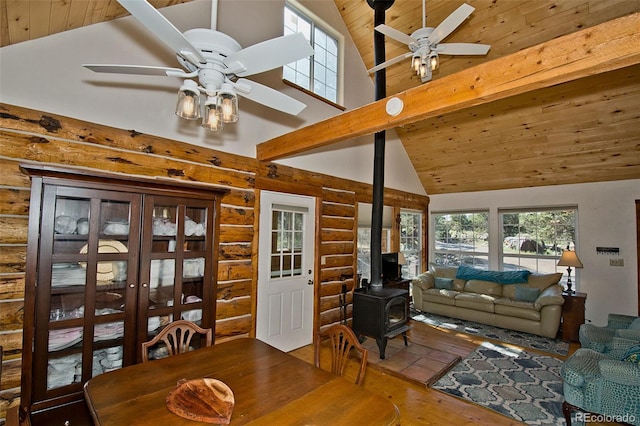 living room with ceiling fan, hardwood / wood-style flooring, a wood stove, rustic walls, and high vaulted ceiling