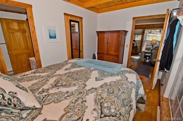 bedroom with beamed ceiling, baseboard heating, hardwood / wood-style floors, and wood ceiling