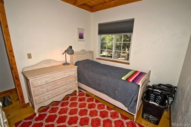 bedroom with beamed ceiling, dark wood-type flooring, and wooden ceiling