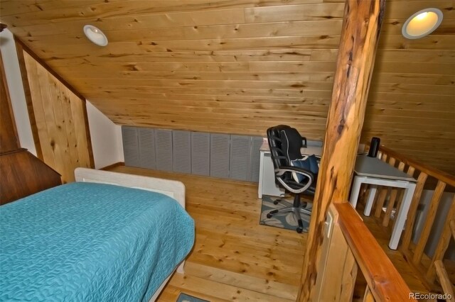 bedroom with wood walls, wood-type flooring, and vaulted ceiling