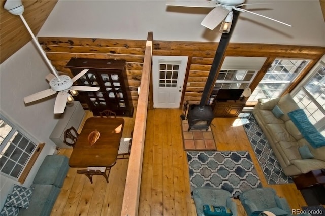 living room featuring wood-type flooring, log walls, and ceiling fan