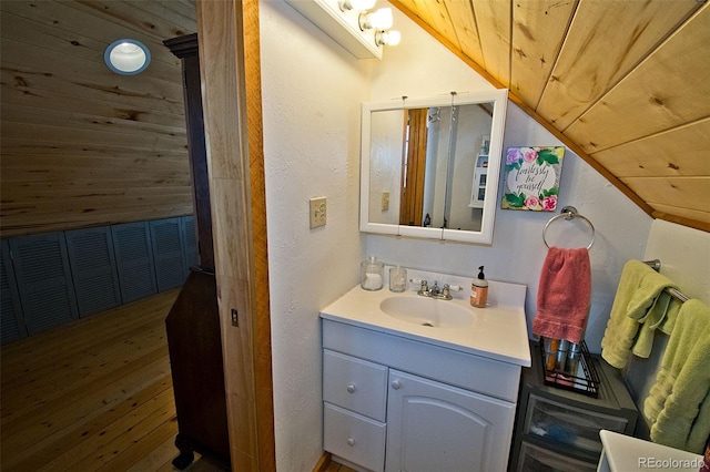 bathroom featuring vanity, wood-type flooring, wooden walls, vaulted ceiling, and wood ceiling