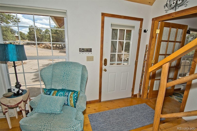 doorway featuring baseboards, stairs, and wood finished floors