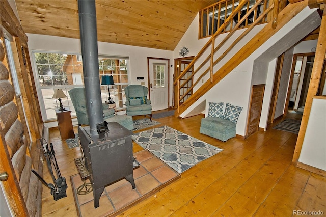 living area with vaulted ceiling, wood ceiling, a wood stove, and hardwood / wood-style floors