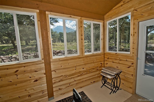 unfurnished sunroom with wooden walls, a wealth of natural light, and lofted ceiling