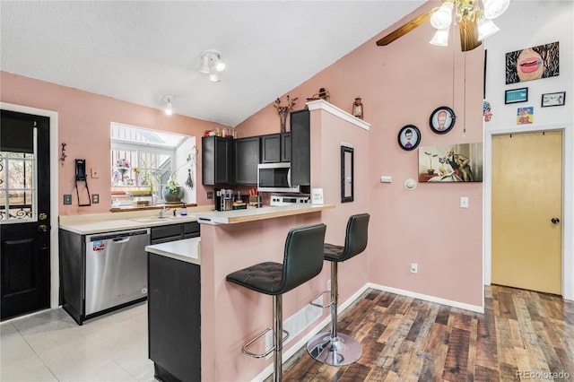 kitchen featuring lofted ceiling, sink, a breakfast bar, stainless steel appliances, and kitchen peninsula