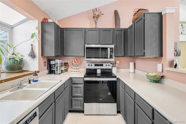 kitchen featuring gray cabinetry, sink, stainless steel appliances, and a textured ceiling