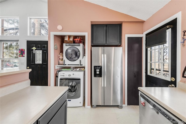 kitchen featuring stainless steel appliances, a healthy amount of sunlight, lofted ceiling, and stacked washer and dryer