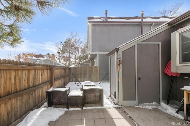 snow covered patio featuring a shed