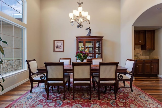 5055 Mcclure Ln, Castle Rock, CO 80108 - dining space with dark wood finished floors, a chandelier, arched walkways, a high ceiling, and baseboards
