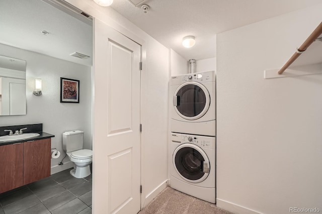 2240 N Clay St Unit 406, Denver, CO 80211 - washroom with stacked washer / drying machine, baseboards, and dark tile patterned flooring
