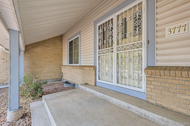 entrance to property with covered porch and brick siding