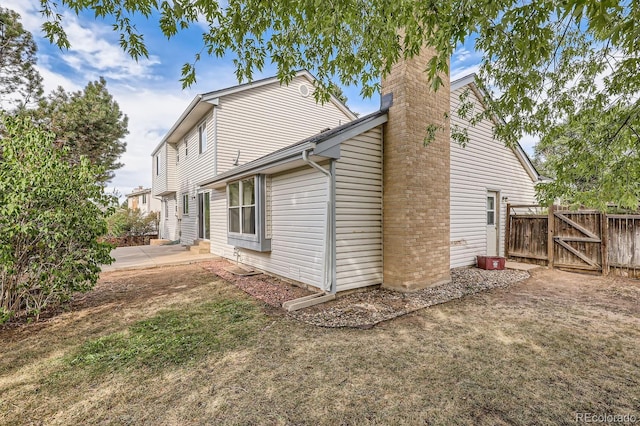 view of property exterior featuring a chimney, entry steps, a gate, a patio area, and fence