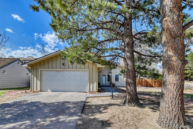 6486 Hawkeye Cir, Colorado Springs, CO 80919 - view of front of house with aphalt driveway, a garage, board and batten siding, and fence