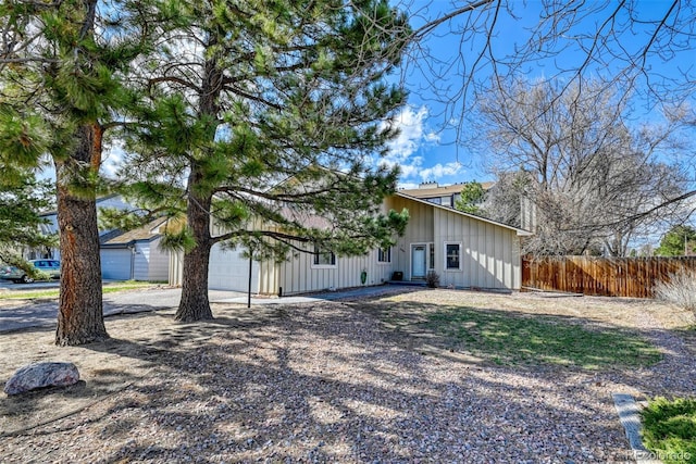 6486 Hawkeye Cir, Colorado Springs, CO 80919 - view of side of home with driveway, an attached garage, fence, and board and batten siding