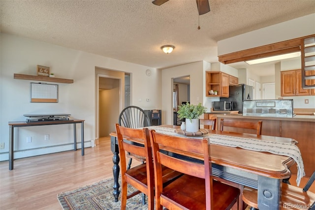 6486 Hawkeye Cir, Colorado Springs, CO 80919 - dining room with light wood finished floors, baseboard heating, ceiling fan, and a textured ceiling
